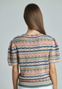 Gebreid truitje met korte mouwen in een gestructureerd patroon in roze, groen, blauw en beige. Heeft een gekarteld decollet é en een geribbelde zoom.