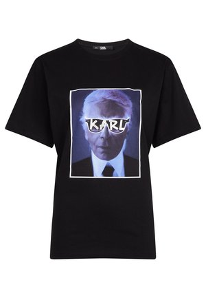 Schwarzes T-Shirt mit kurzen Ärmeln und einem blau getönten Porträt eines Mannes, der weiße Sonnenbrillen trägt, auf deren Gläsern das Wort "KARL" abgebildet ist.