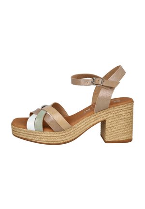 Sandalias de tiras en color beige y metálico con un tacón ancho, que presentan una base de esparto trenzada y una textura brillante en un diseño multicolor.
