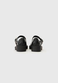 Black leather sandals with a chunky heel, open back design, and adjustable strap. Smooth texture with minimal stitching details.