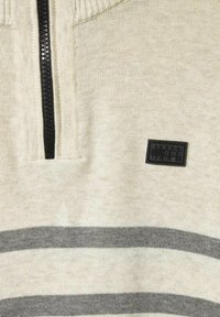 Jasnoszary sweter w paski z wysokim kołnierzem, czarnym zamkiem błyskawicznym, teksturowanym materiałem dzianinowym i czarną prostokątną metką z logo.