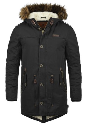 Parka noire avec capuche doublée de fourrure, dotée de poches poitrine et latérales, fermeture éclair et accents en cuir marron. Doublure en tissu crème.