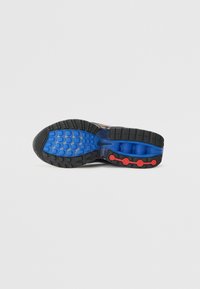 Black outsole with blue and red accents, featuring a textured surface and visible cushioning elements, designed for comfort and traction.