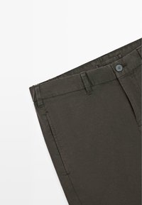 Dunkelolivgrüne Hose mit Gürtelschlaufen, Vordertaschen, Knopfverschluss und sichtbaren Nähten auf weißem Hintergrund.