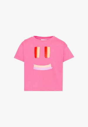 T-shirt rose à manches courtes avec un motif visage souriant présentant deux yeux verticaux rouge-orange et une bouche incurvée de couleur pastel.