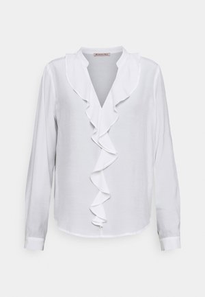 Blusa blanca de manga larga con escote en V y detalle de volantes en la parte frontal. Fabricada con una tela suave de textura ligeramente transparente.