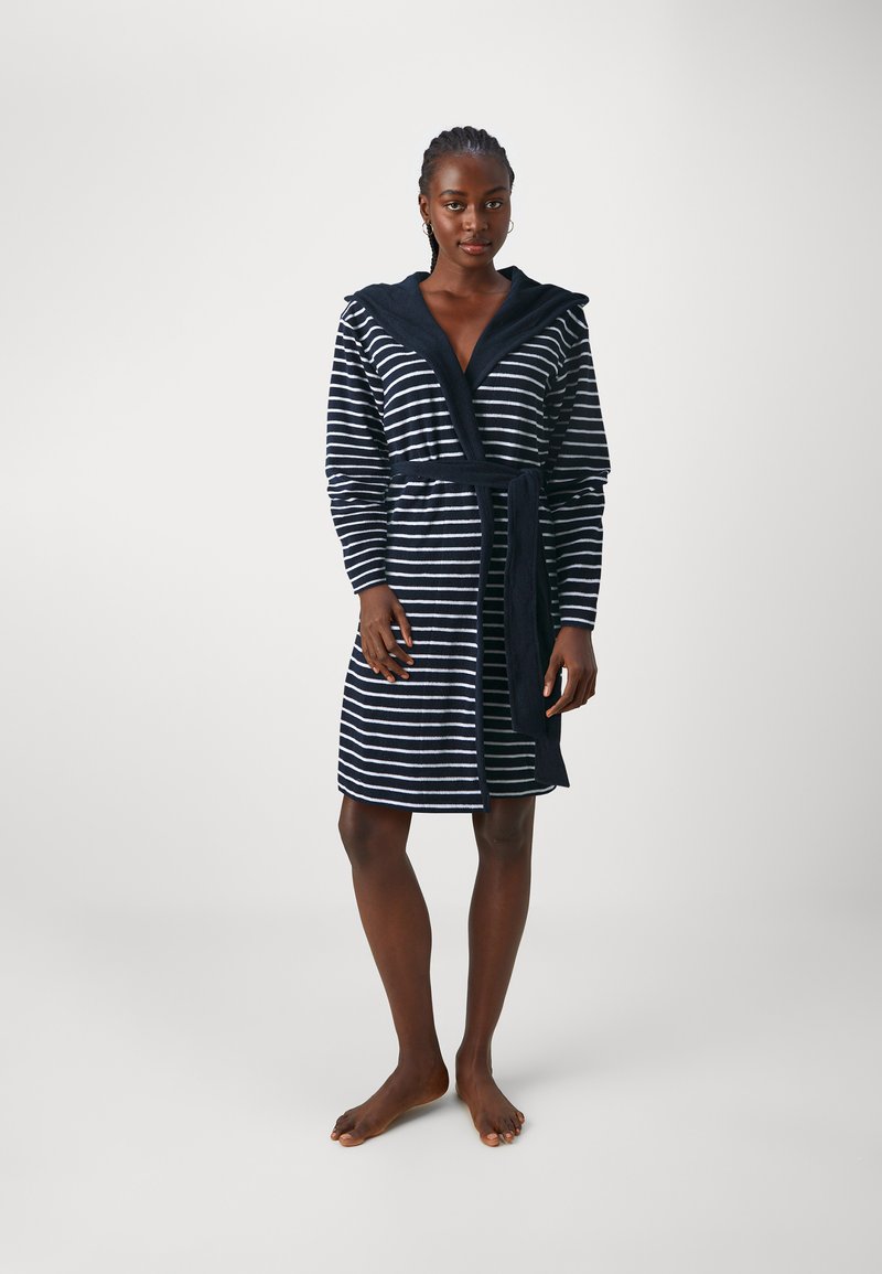 Accappatoio a righe in blue navy con strisce orizzontali bianche, dotato di cappuccio, cintura e maniche lunghe, con una texture morbida. Modello a piedi nudi in posizione eretta.