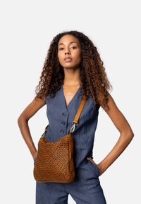 Borsa a spalla in pelle intrecciata marrone con superficie texturizzata, tracolla removibile e dettagli in hardware dorato. Presenta una forma morbida.