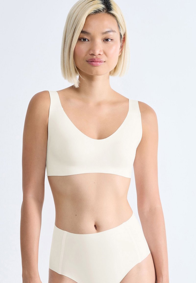 Cremefarvet bralette med brede stropper og V-hals-design, parret med højtaljede briefs i samme tone, lavet af glat stof.