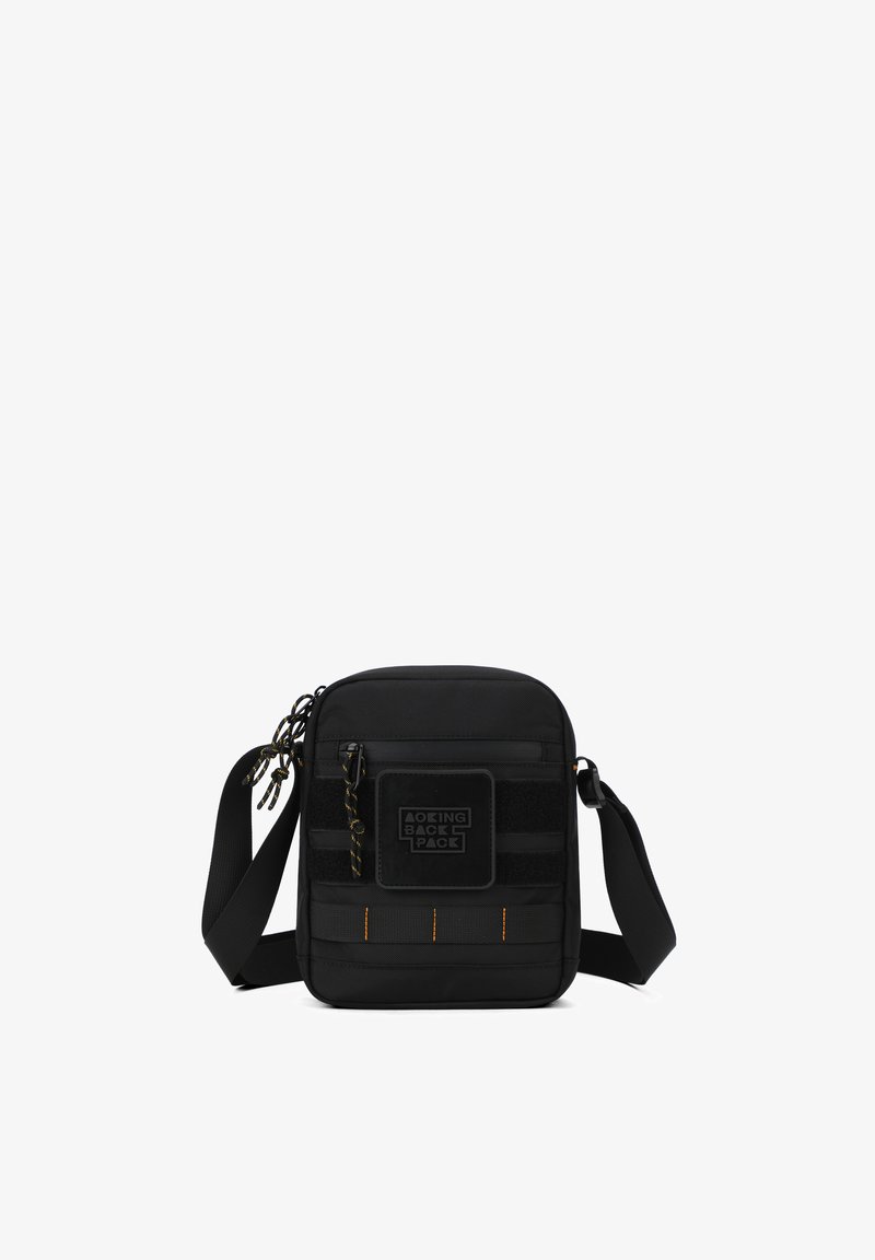 Petit sac bandoulière noir compact avec sangle réglable, poche avant zippée, étiquette cousue et détails de surpiqûres jaunes.