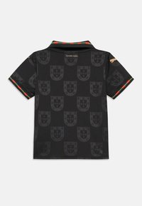 Čierne polo tričko s tónovaným vzorom štítu, golierom s pruhmi v zelenej a červenej farbe a zlatým logom značky na ramene.