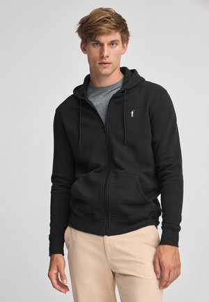 Zwarte rits-hoodie met een kangoeroezak, verstelbare trekkoordkap en geborduurd wit logo op de linkerkant van de borst. Zachte stoftextuur.