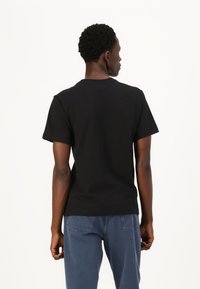 Svart crew-neck t-skjorte med korte ermer, laget av bomull, med et ensfarget design uten mønstre eller logoer.