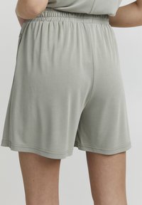 Light grey shorts made of soft fabric with an elastic waistband. Features a relaxed fit and a smooth texture, ending above the knee.