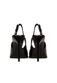 Sandalias de tacón alto de charol negro con diseño de tiras al talón, que presentan un acabado brillante y tacones de aguja afilados.