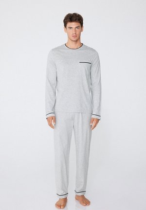 Ensemble de pyjama à manches longues gris en tissu doux, comportant une poche accent noire, un contour contrastant et un pantalon à jambes droites.
