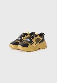 Sorte og guld sneakers med mesh-paneler, teksturerede detaljer og rundede såler. Har sorte snørebånd og et logopatch på tungen.
