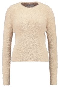 Sammetslen beige tröja med långa ärmar, rund halslinje och textilstruktur. Mjuk och mysig i sitt utseende, med en figurnära siluett.