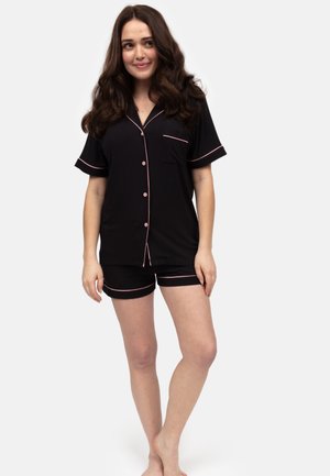 Ensemble de pyjama noir à manches courtes avec un passepoil rose, comprenant une chemise à boutons, une poche et un short assorti avec une taille élastique.
