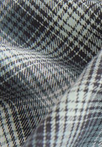 Tissu tissé avec un motif pied-de-poule dans des tons de bleu foncé et gris clair, présentant une texture lisse et des lignes diagonales distinctes.