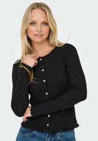 Czarny żebrowany kardigan z długim rękawem, zapinany na pięć guzików, z postrzępionymi detalami u dołu. Wykonany z teksturowanej tkaniny, z okrągłym dekoltem.