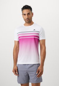 Weißes T-Shirt mit kurzen Ärmeln, das einen rosa Farbverlauf, horizontale Streifen und ein kleines schwarzes Logo auf der Brust aufweist. Kombiniert mit grauen Shorts.