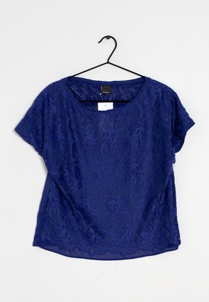 Mørkeblå kortærmet bluse med blomsterbroderi, letvægtsstof, rund halsudskæring og løstsiddende pasform. Hænger på en sort krog.