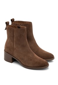 Brązowe zamszowe botki do kostek z kwadratowym noskiem, zamkiem błyskawicznym z boku i niskim, blokowym obcasem. Posiadają pętelkę z tyłu dla łatwego zakupu.