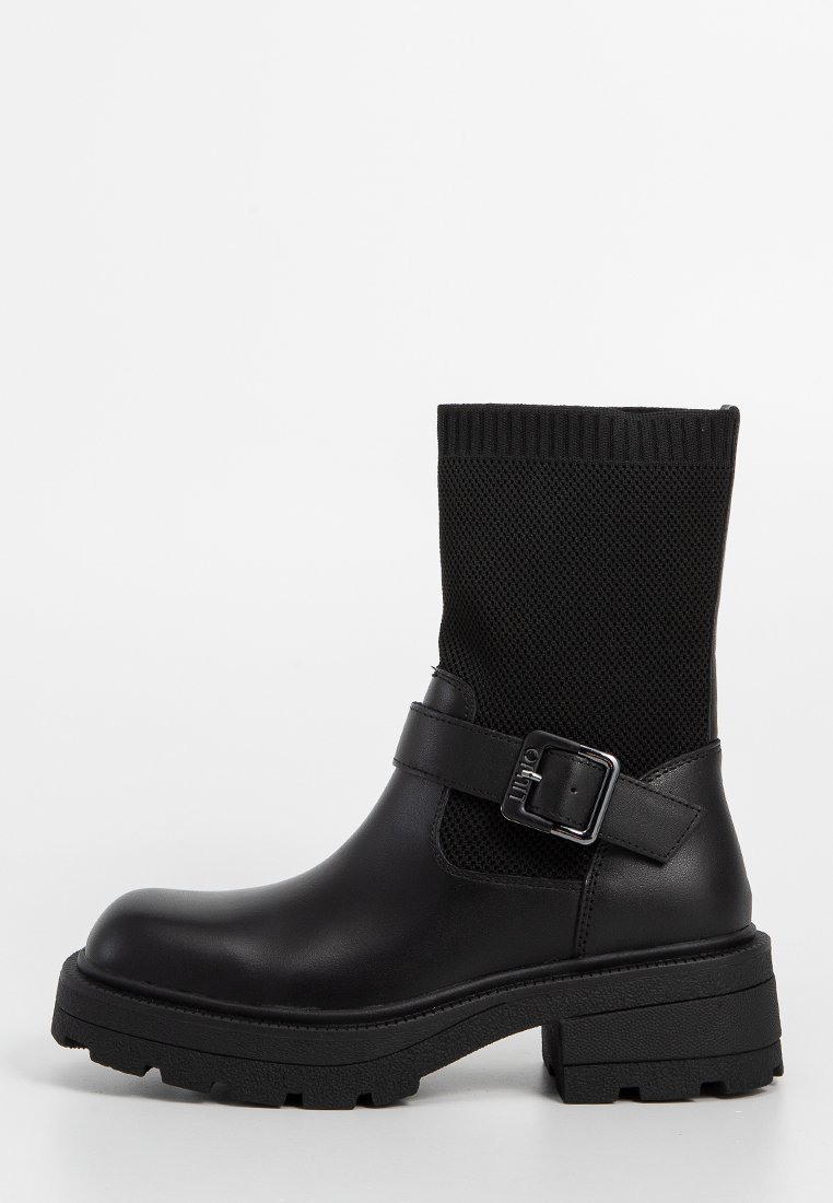 Czarne botki do kostki z teksturowaną górą z dzianiny, gładką syntetyczną dolną częścią, regulowanym paskiem z klamrą oraz masywną gumową podeszwą.