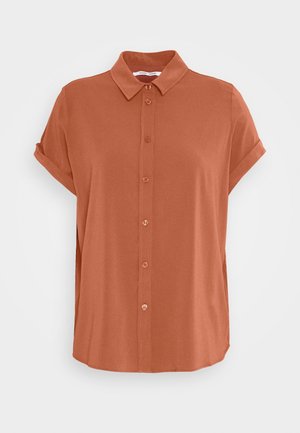 Chemise à manches courtes boutonnée de couleur rouille avec col pointu et manches retroussées, présentée sur un fond clair uni.