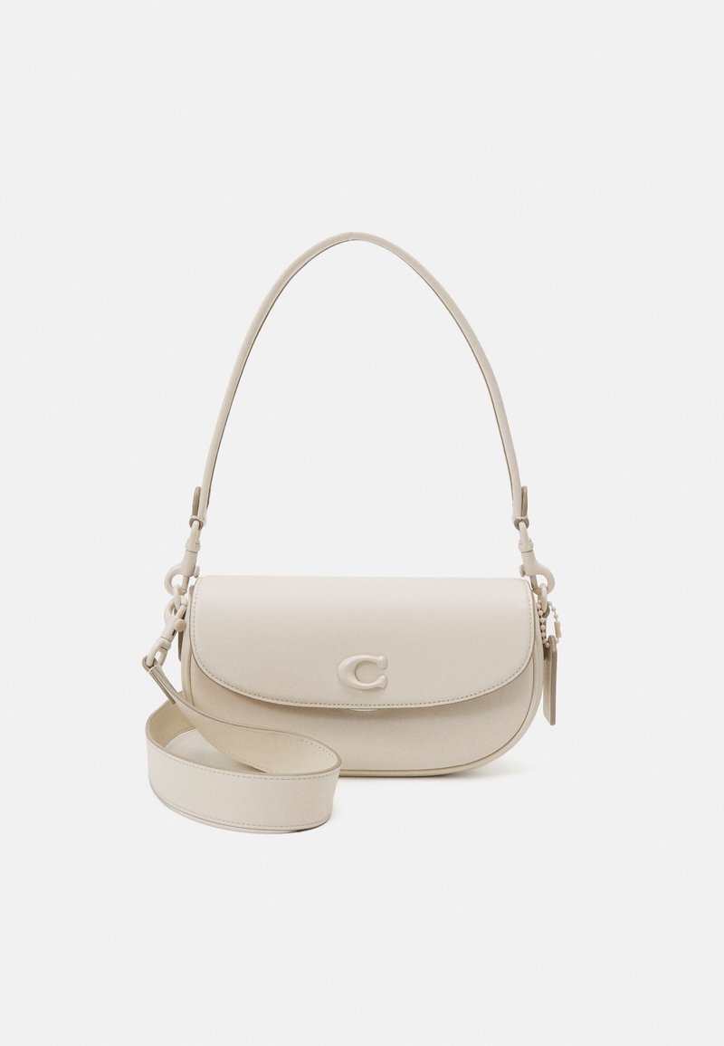 Sac à bandoulière en cuir couleur crème avec fermeture à rabat, logo embossé à l'avant et deux sangles réglables sur fond blanc uni.