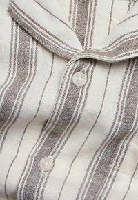 Gestreepte shirt met een witte en bruine linnen textuur, voorzien van een kraag en een knoopsluiting. De stof vertoont fijne horizontale strepen.