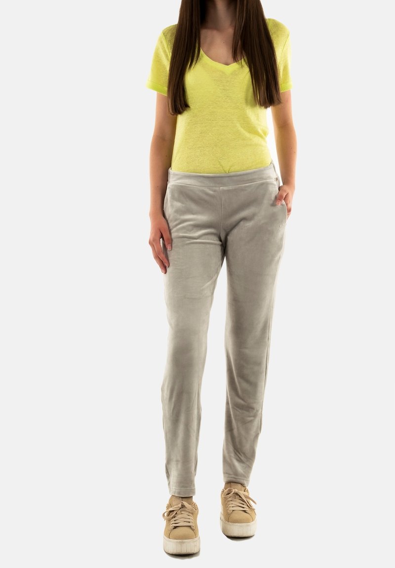 Camiseta amarilla de cuello en V, pantalones suaves en gris claro con bolsillos laterales, combinados con zapatillas beige, con un ajuste relajado y una textura suave.