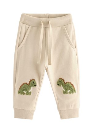 Beige sweatpants til småbørn med ribbet talje og manchetter, snøre, sidelommer og grønne dinosaur-patches på knæene.