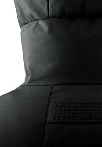 Chaleco acolchado negro con un alto cuello, textura suave y costuras visibles. Presenta una cinta de webbing horizontal en la parte posterior para ajuste.