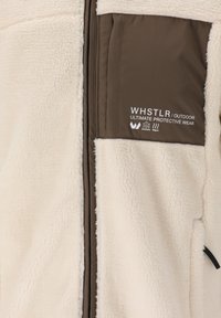 Fleecejacka i krämfärg med en brun inre panel. Har dragkedjestängning, framficka och logotypdetaljer. Mjuk textur hela vägen.