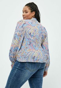 Blå mønstret bluse med lange ærmer, prydet med paisleymønster i pink, gul og marineblå. Sættes sammen med mørke denimjeans.