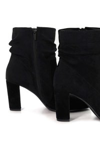 Black suede ankle boots with a tapered toe, slouchy upper design, and a side zipper. Chunky block heel for added stability.