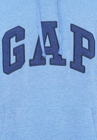 Ανοιχτό μπλε φούτερ με σκούρα μπλε γράμματα "GAP", διαθέτει τσέπη καγκουρό και κορδόνια στο ίδιο χρώμα. Μαλακό, ελαφρύ ύφασμα.