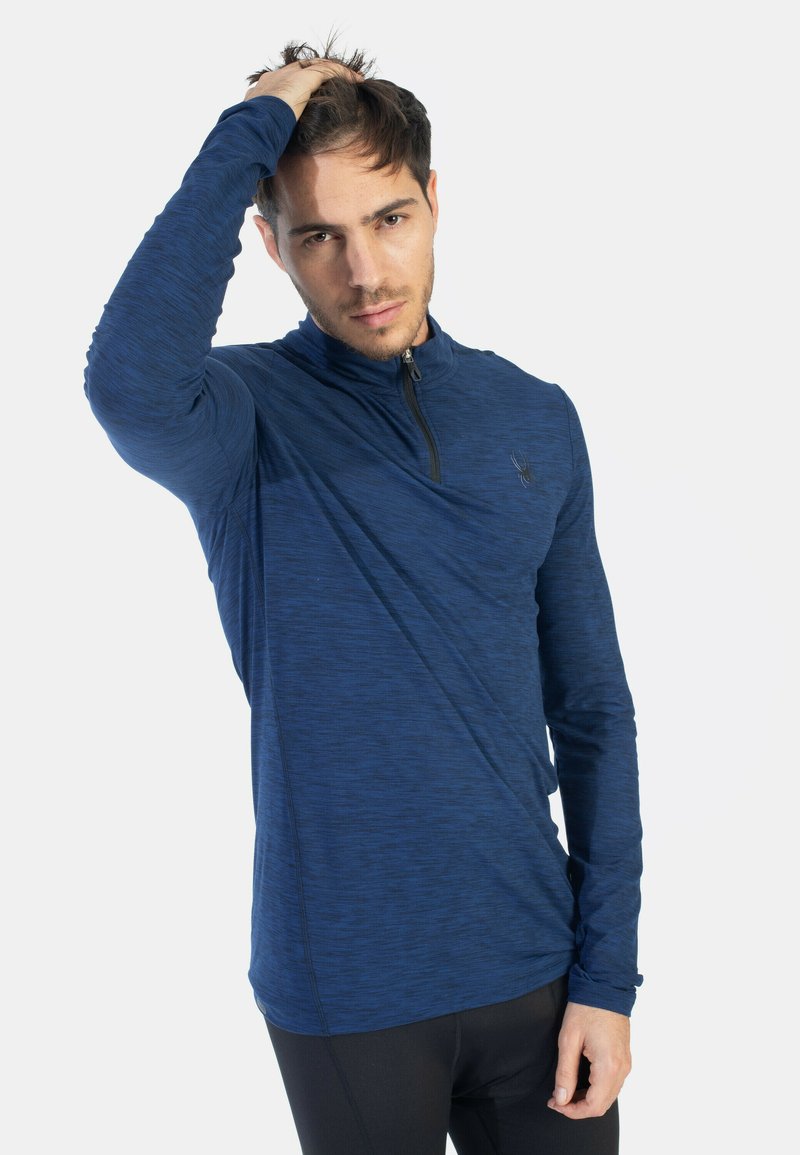 Maglietta a maniche lunghe con zip in tessuto strutturato blu scuro. Presenta un colletto alto e un marchio discreto. Design aderente con costruzione senza cuciture.