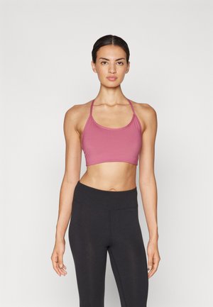 Reggiseno sportivo rosa con spalline sottili, design senza cuciture e vestibilità cropped, abbinato a leggings neri a vita alta, su uno sfondo neutro.