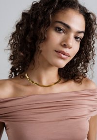 Top roz deschis, cu umerii lăsați la vedere, cu textură plisată și siluetă elegantă, completat de un colier curbat din aur.