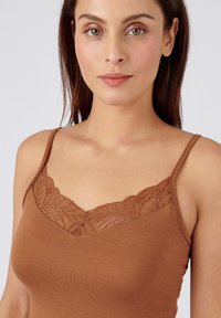 Brown camisole with lace trim along the neckline, featuring thin adjustable straps and a smooth, fitted design.