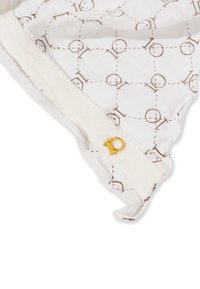 Tissu blanc avec un motif géométrique marron, bordé d'une garniture texturée blanche et d'un petit accent doré marqué de "10".