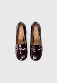 Dype, glansende laklær loafers med rektangulært tåparti, pynte med en gullfarget detalj og en liten blokkhæl. Innvendig er de beige.