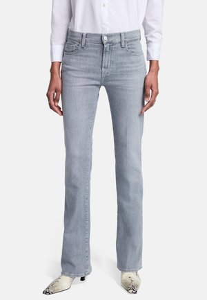 Jeans a zampa d'elefante in denim grigio chiaro con vita media, cinque tasche e cuciture sottili. Abbinati a stivali alla caviglia con stampa serpente.