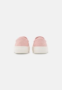 Sapatos slip-on em camurça rosa com sola de borracha branca, apresentando um bico arredondado e detalhes de costura mínima na parte de trás.
