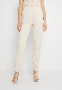 Beige sweatpants met een elastische tailleband en taps toelopende boorden. Gemaakt van zachte stof met een gladde textuur, ontworpen voor comfort.
