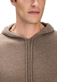 Brun hættebluse lavet af blødt stof, med en frontlomme og snor. Teksturen er glat med et let meleret mønster.