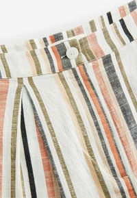 Tissu rayé avec des lignes verticales dans des tons de blanc, rose, olive et noir ; comprend un bouton blanc et un détail de pinces.